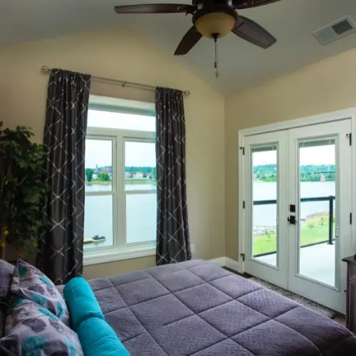 Stylish bedroom featuring updated windows and doors with waterfront views - window replacement by Home Makeover.